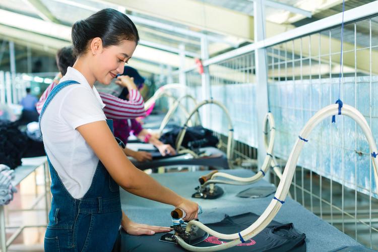 服装产品在纺织工厂贴标过程技术工人服装厂里一条生产线上正在工作的